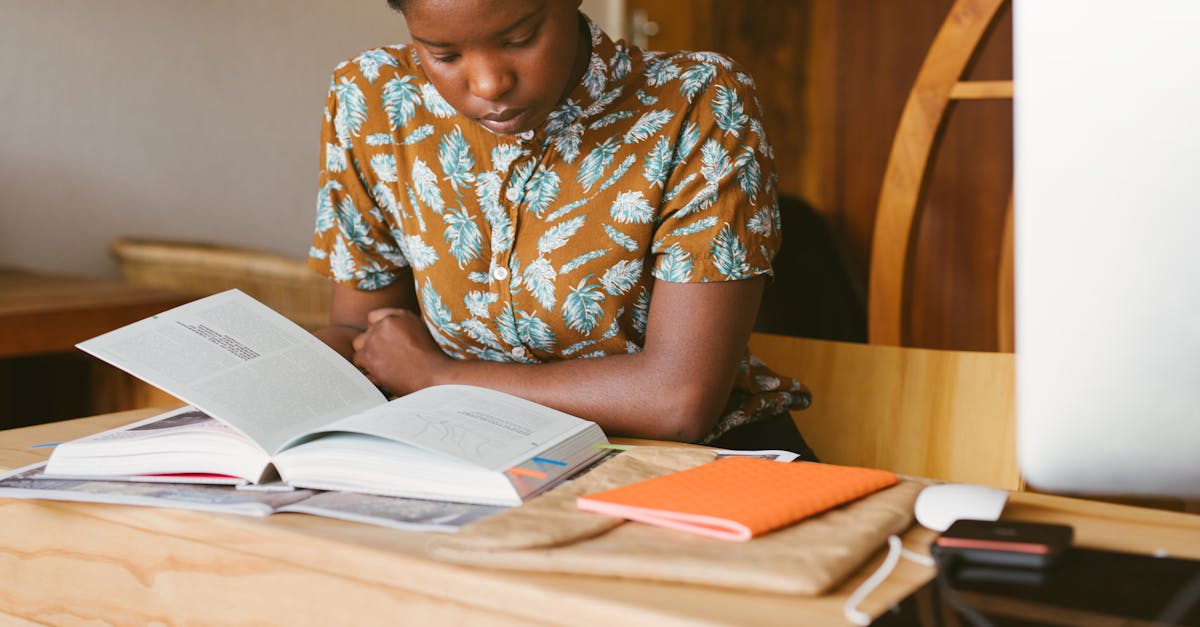 A young woman studies a book at her desk in a warm, indoor setting, illustrating a calm study environment.